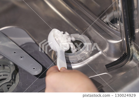 Person adding detergent to dishwasher for cleaning and maintenance in a home Person adding detergent to dishwasher for cleaning and maintenance in a home 130024929