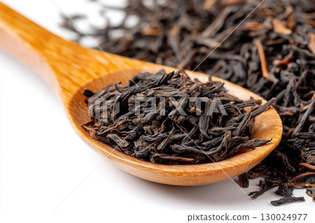 Dry black tea leaves in a wooden spoon isolated on white background. Pile of Dried fermented tea. Black Tea Leaves Heap. Close Up, Macro. Texture. Copy Space. Dried Tea. Abstract Food Drink Backdrop. 130024977