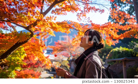 Woman looking at autumn leaves 130025343