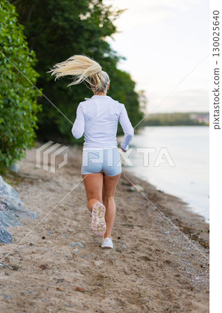 Woman Running on a Scenic Beach Trail Next to the Water Woman Running on a Scenic Beach Trail Next to the Water 130025640