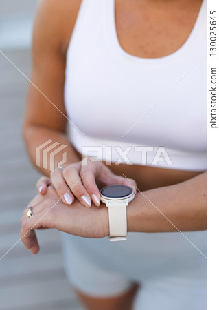 Young woman using a smartwatch during an outdoor fitness session 130025645