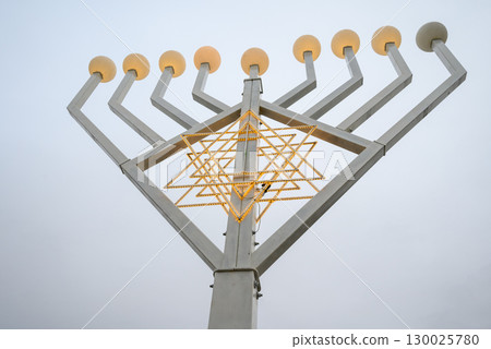 A large menorah with multiple arms and a star of David design, against a gray sky 130025780