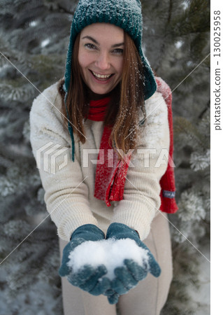 Laughing Woman Holding Snow on a Snowy Day in Winter 130025958