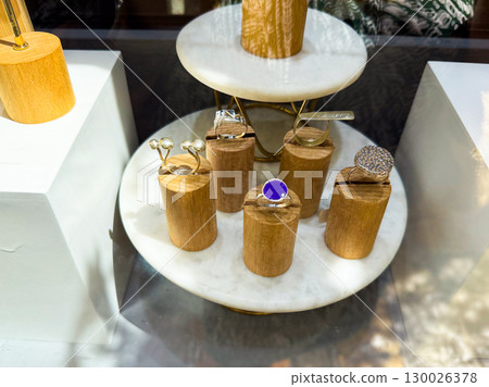 Modern jewelry rings displayed on wooden stands in showcase. Retail design and lifestyle accessory presentation in luxury market. 130026378