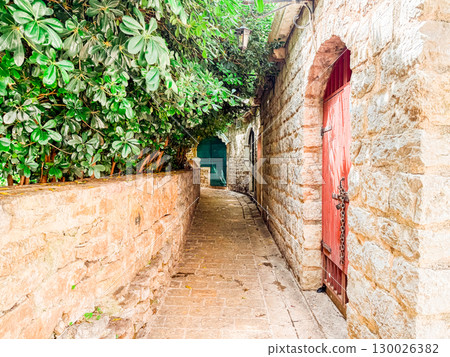 Narrow alley with stone walls and doors in old town. Cultural charm and historic character of European urban architecture. 130026382