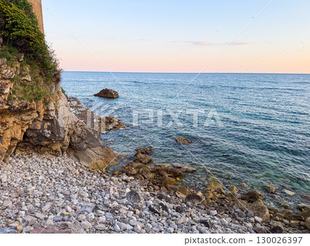 Rocky seashore with waves and horizon at sunset in Montenegro. Travel, relaxation, nature and exploration along a scenic coastal marine landscape. 130026397
