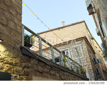 Stone houses with balcony and string lights in a narrow alley. Travel, culture and historic architecture in an old European urban destination. 130026399