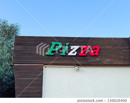 Pizza sign on a wooden wall of a cafe. Food culture, urban lifestyle and dining tradition in a modern travel destination. 130026400