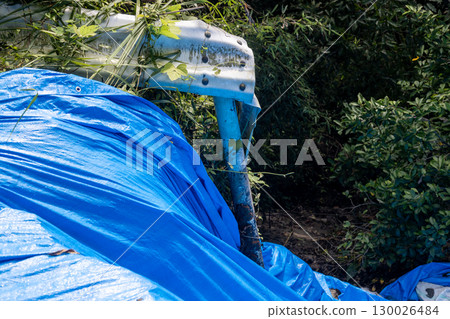 A road that collapsed due to heavy rain and is being protected with blue tarps A road that collapsed due to heavy rain and is being protected with blue tarps 130026484