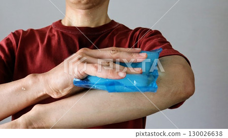 A person cooling their arm with an ice pack A person cooling their arm with an ice pack 130026638