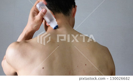 Back view of a person applying a compress to the body Back view of a person applying a compress to the body 130026682