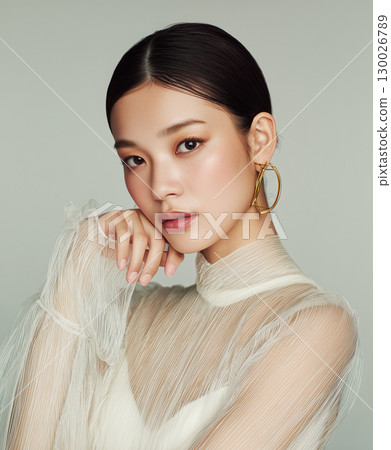 Portrait of a Japanese woman wearing gold earrings and a sheer top (fashion, beauty, advertising) 130026789