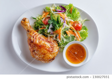 Roasted chicken leg with salad and tomato sauce on a white plate, top view, isolated on a light background. Baked chicken. Healthy food for slimming the body in a weight loss program. Gourmet dinner 130027031