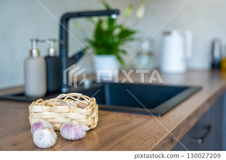 Basket with Chinese single clove garlic on kitchen countertop. Natural cooking ingredient, organic vegetable, and culinary preparation. Basket with Chinese single clove garlic on kitchen countertop. Natural cooking ingredient, organic vegetable, and culinary preparation. 130027209