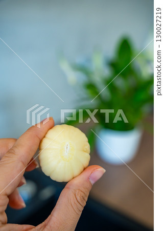 Female hand holding peeled Chinese single clove garlic. Fresh ingredient, natural flavor, and kitchen preparation. Female hand holding peeled Chinese single clove garlic. Fresh ingredient, natural flavor, and kitchen preparation. 130027219