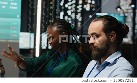 Diverse team of analysts reviewing annual data reports in after hours meeting, developing internal communication to ensure productivity. Working on enterprise development plans. Camera B. 130027291