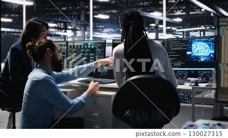 Data center software developers using machine learning algorithms to analyze large datasets. Server hub IT experts cooperating, using AI neural networks to recognize data patterns, camera A Data center software developers using machine learning algorithms to analyze large datasets. Server hub IT experts cooperating, using AI neural networks to recognize data patterns, camera A 130027315