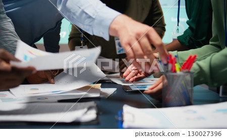 Diverse business team exchanging insights and forecasting diagrams in a late night meeting, reviewing financial data analytics and business intel. Advisory board collaboration. Camera A. 130027396