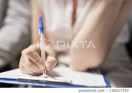 Close up of candidate filling in registration forms for job application and interview, ensuring a great recruitment process and successful meeting with the HR. Writes down qualifications. 130027397