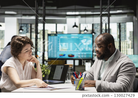 HR professional and job seeker engaging in a career advisory session during the hiring process, reviewing a CV document and discussing employment opportunity and talent acquisition. Workforce. 130027429