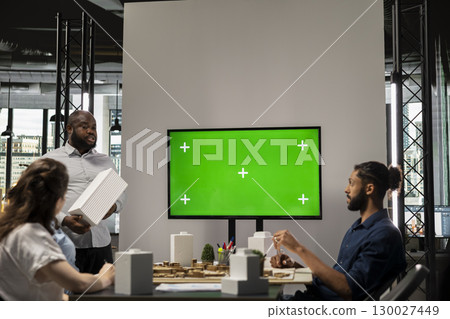 Engineers real estate staff review blueprints with chroma key screen, focusing on zoning regulations and infrastructure improvements for a modern residential housing project. Innovation hub. Engineers real estate staff review blueprints with chroma key screen, focusing on zoning regulations and infrastructure improvements for a modern residential housing project. Innovation hub. 130027449