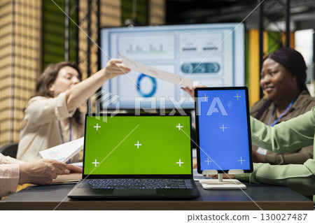 Diverse business associates using isolated display in modern office session, supporting digital planning and studying performance data reports. Strategic thinking and determination. 130027487