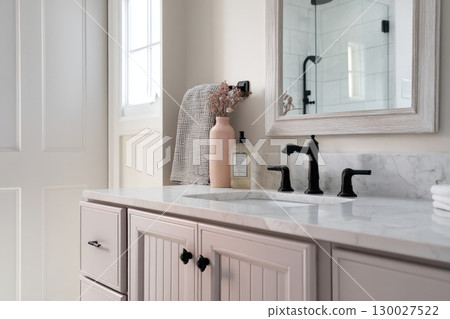 Grey bathroom vanity with white walls, mirror and marble countertop, black hardware. Clean aesthetic background. Home interior room design. Gray cabinet in a bathroom 130027522