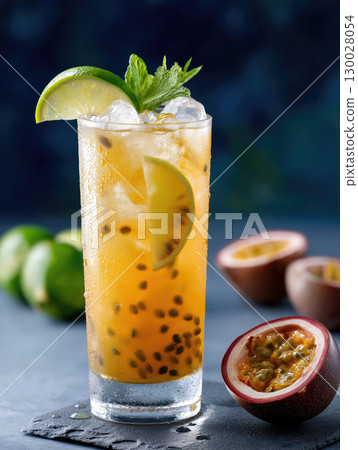 A cold tropical beverage with passion fruit and mint sits on a textured surface. 130028054