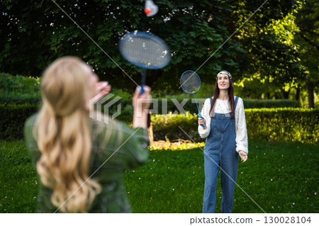Friends enjoy a lively game of badminton in a vibrant green park 130028104
