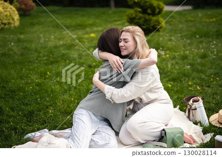 Friends enjoying a heartfelt embrace during a sunny day in the park Friends enjoying a heartfelt embrace during a sunny day in the park 130028114