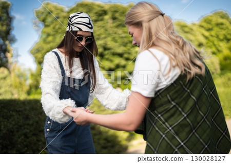 Fashionable friends enjoy a sunny day outdoors while sharing a joyful moment 130028127