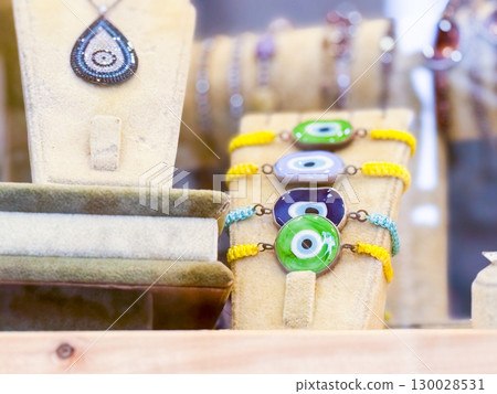 Colorful eye charm bracelets displayed on a stand with necklace in background. The photo conveys protection, belief, tradition, fashion accessory and cultural symbolism. 130028531