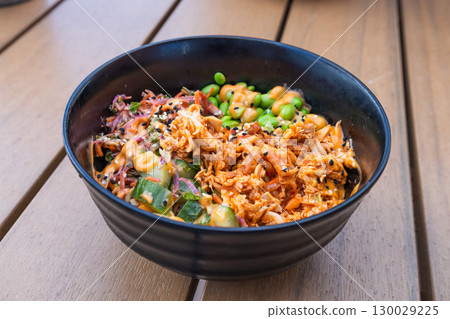 Spicy Fried Rice Bowl with Scallions in Black Bowl on Wooden Table, Asian Comfort Spicy Fried Rice Bowl with Scallions in Black Bowl on Wooden Table, Asian Comfort 130029225