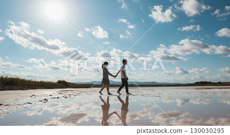 兩個人在倒映著鏡子的鹽湖中牽手 130030295