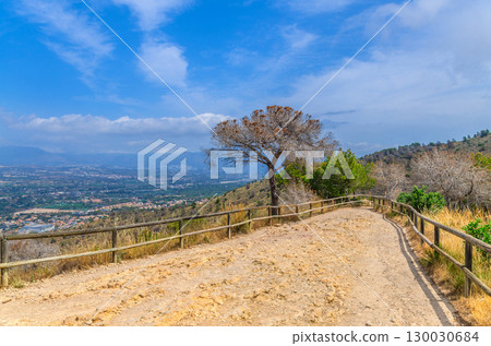 Road with wooden fence on mountain hill Serra Gelada natural park and aerial view of La Nucia Hills valley in summer day, Valencian Community, Spain Road with wooden fence on mountain hill Serra Gelada natural park and aerial view of La Nucia Hills valley in summer day, Valencian Community, Spain 130030684