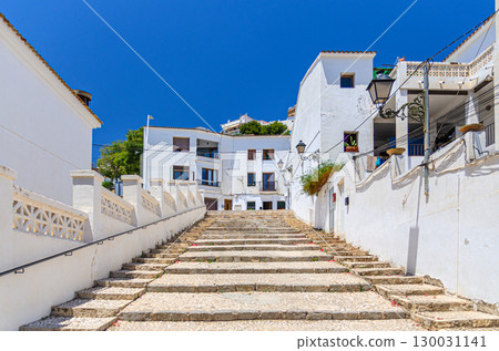Altea old town narrow street with staircase steps, typical white houses traditional buildings in sunny day, Altea city historical centre Casco Antiguo, Alicante province, Valencian Community, Spain Altea old town narrow street with staircase steps, typical white houses traditional buildings in sunny day, Altea city historical centre Casco Antiguo, Alicante province, Valencian Community, Spain 130031141