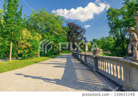 Hofgarten Court Gardens with path and stone fence with sculptures of Wurzburg Residence Residenz in Wurzburg old town in sunny summer day, Lower Franconia region, Bavaria state, Germany 130031148