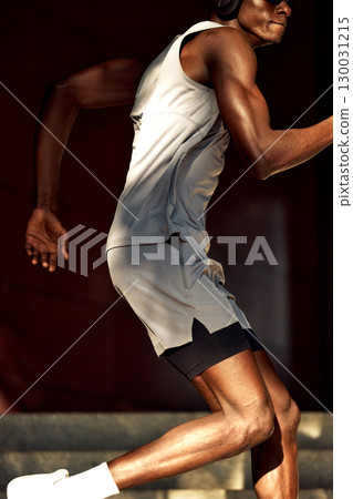 Athletic individual running outdoors in sporty attire with headphones Athletic individual running outdoors in sporty attire with headphones 130031215