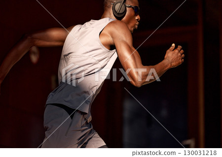 Athlete sprinting with headphones in an urban setting during daylight 130031218