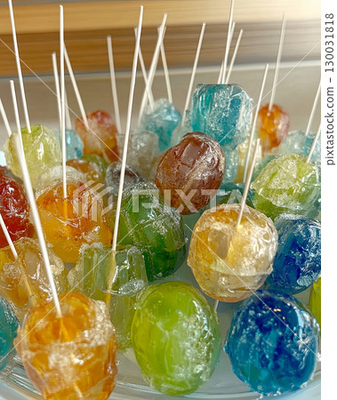 Colorful candy lollipops arranged in a bowl with sticks 130031818