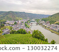 Scenic view of a picturesque river valley surrounded by lush vineyards and charming village architecture under a cloudy sky, showcasing natural beauty 130032274