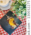 Delicious dessert featuring chocolate layers and fresh lemon slices served on a slate plate with a coffee cup and greenery in the background 130032275
