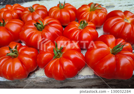 Fresh, ripe heirloom tomatoes arranged on rustic wooden surface, showcasing vibrant colors and unique shapes, perfect for culinary presentations 130032284