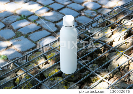 White thermo stainless bottle with refreshing water stay on the nature. White thermo stainless bottle with refreshing water stay on the nature. 130032676