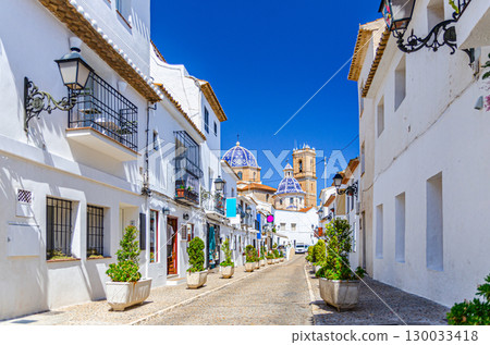 Altea old town narrow street Sant Miquel with Iglesia Nuestra Senora del Consuelo catholic church, typical white houses buildings, Altea city historical centre Casco Antiguo, Alicante province, Spain 130033418