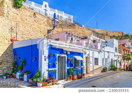 Alicante old town Santa Cruz with narrow street, typical white houses with flowers and plants and Ermita de la Santa Creu d'Alacant church in Alicante city historic centre, Valencian Community, Spain Alicante old town Santa Cruz with narrow street, typical white houses with flowers and plants and Ermita de la Santa Creu d'Alacant church in Alicante city historic centre, Valencian Community, Spain 130033555