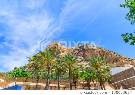 Mount Benacantil rock with Castell de Santa Barbara castle and Parque de La Ereta park with palm trees in old town Alicante city historical centre in sunny summer day, Valencian Community, Spain 130033634