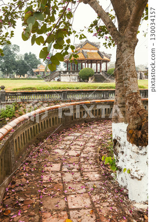 Curved stone path with scattered flower petals leading to traditional pavilion in Hue Imperial City Vietnam 130034157