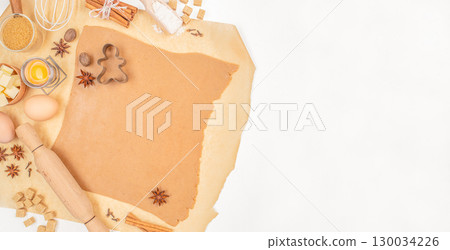 Gingerbread dough with cookie cutter and baking ingredients on parchment paper. Long banner format. top view. copy space Gingerbread dough with cookie cutter and baking ingredients on parchment paper. Long banner format. top view. copy space 130034226