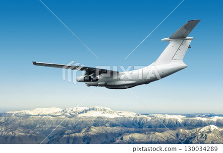 White wide body cargo airplane flies over snow covered mountains White wide body cargo airplane flies over snow covered mountains 130034289